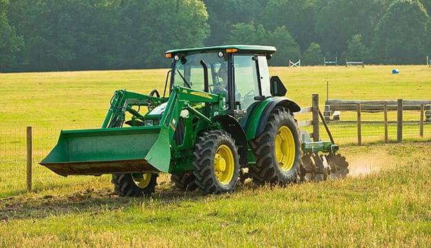 green farm tractor on a field